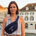 Frau trägt navy-blaue Bauchtasche "The Flow from Züri" von Waswänzi vor Altstadt-Kulisse in Zürich