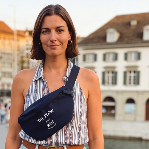 Frau trägt navy-blaue Bauchtasche "The Flow from Züri" von Waswänzi vor Altstadt-Kulisse in Zürich